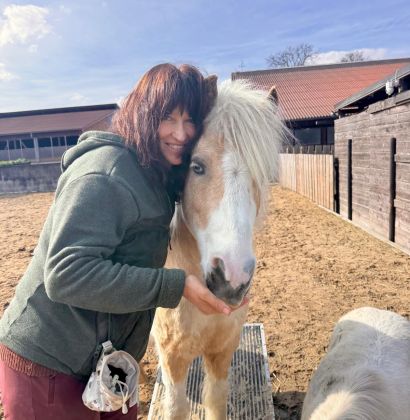Eine lachende Frau, die ein Pferd füttert