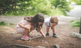 2 Kinder im Wald, die den Boden untersuchen