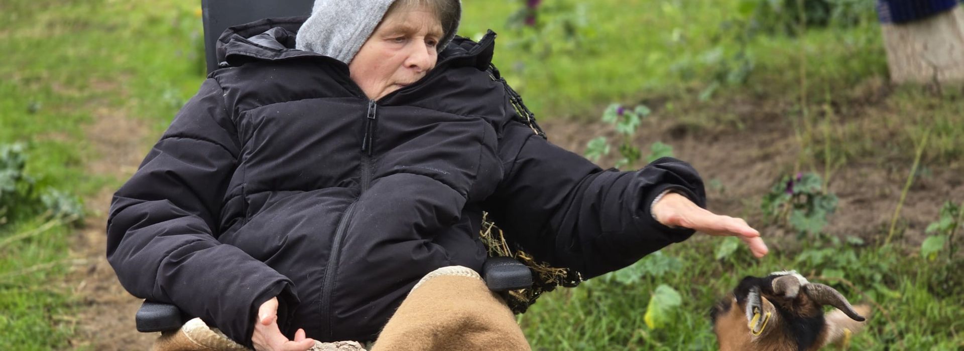 Eine ältere Frau, die eine Ziege streichelt