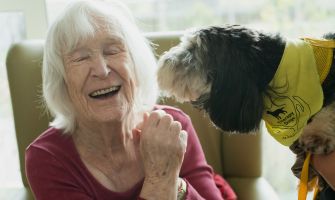 Eine lachende, ältere Frau mit einem Hund