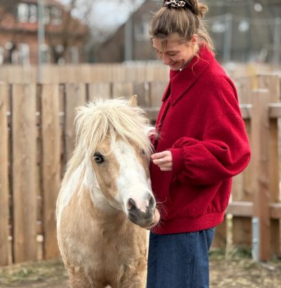 Eine grinsende Frau mit einem kleinen Pferd