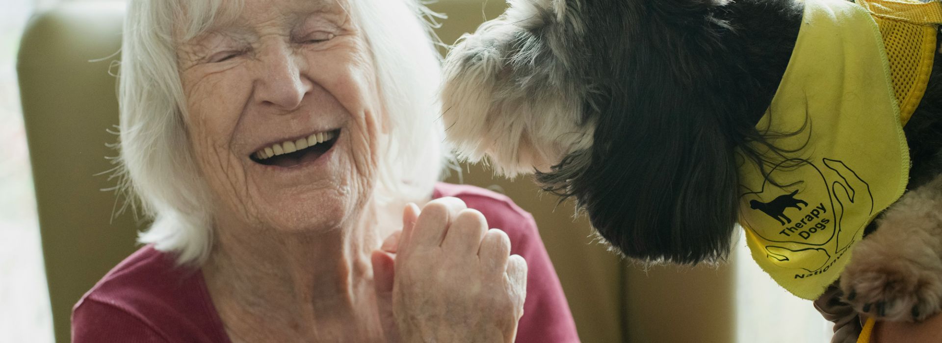Eine lachende, ältere Frau mit einem Hund
